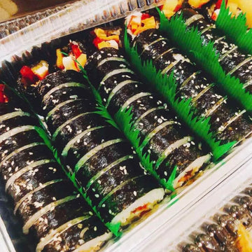 Pork Kimbap with green leaves on a tray