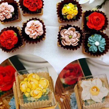 A set of edible cupcakes shaped like flowers with various colorful petals, displayed on a table.