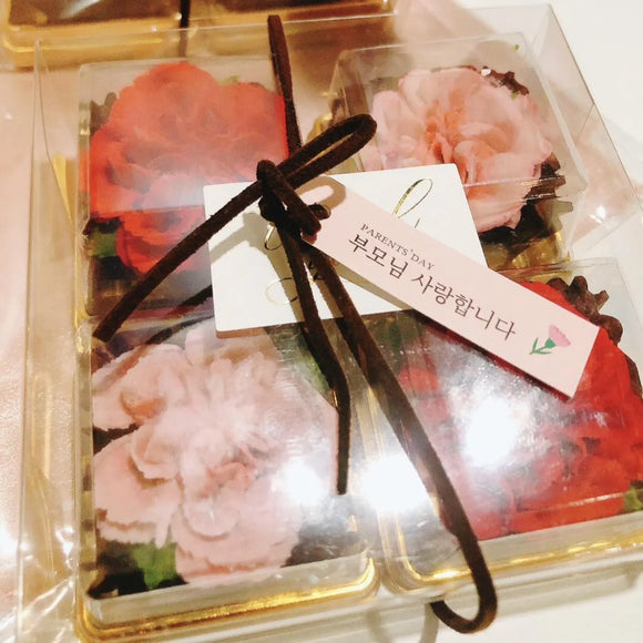 Packaged edible flowers with a decorative bow and a card in a clear plastic container.