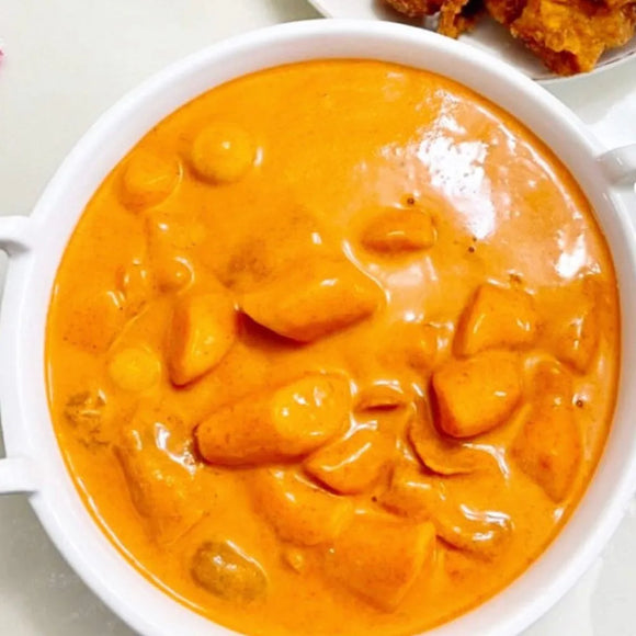 Rich, creamy, and mildly spicy tteokbokki in a white bowl on a light background