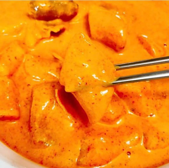 Cup of rose tteokbokki with a chopsticks