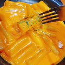 Rose tteokbokki with a fork on a dark plate