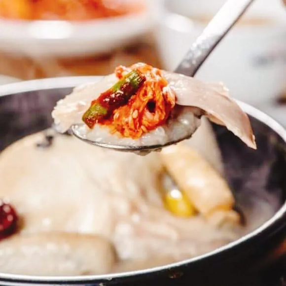 A spoonful of Samgyetang (Korean ginseng chicken soup) with rice and mixed vegetables.