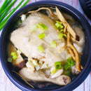 Bowl of Samgyetang Chapssal, a soup vegetables, ginseng and other herbs on a wooden table.