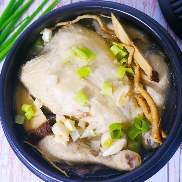 Bowl of Samgyetang Chapssal, a soup vegetables, ginseng and other herbs on a wooden table.
