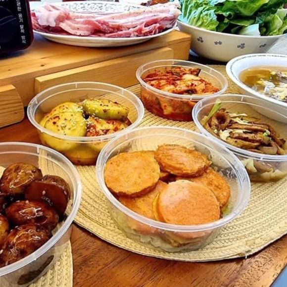 Assorted Korean dishes including kimchi, pickled radishes, and sliced vegetables on a wooden table.