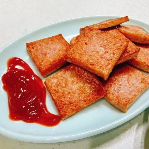 Square pieces of Korean spam on a white plate with a side of ketchup.