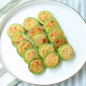 A plate of traditional Korean soegogi aehobakjeon, featuring thin slices of zucchini filled with seasoned beef, arranged in a pattern on a white plate.