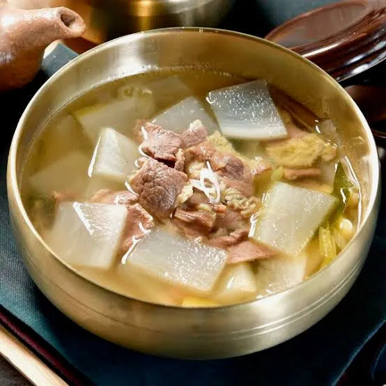 Bowl of soup with meat and radish in a traditional metal container