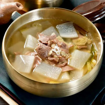 Bowl of soup with meat and radish in a traditional metal container