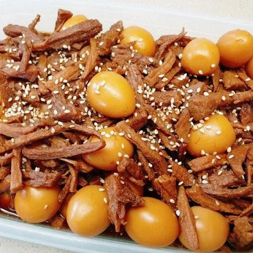 A plate of Korean soy-braised beef, also known as jangjorim, with quail eggs and sesame seeds garnishing the dish.
