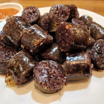 A plate of Korean pork blood sausage, likely soondae, served with a side of ssamjang sauce.