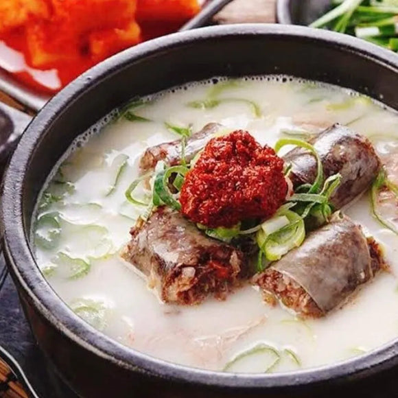 Bowl of soup with meat and vegetables on a wooden table