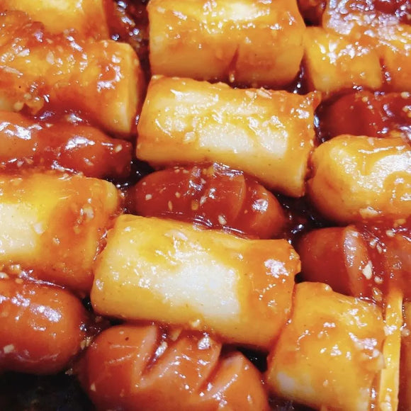 Close-up of Korean street food featuring sausages and rice cakes on a skewer. 