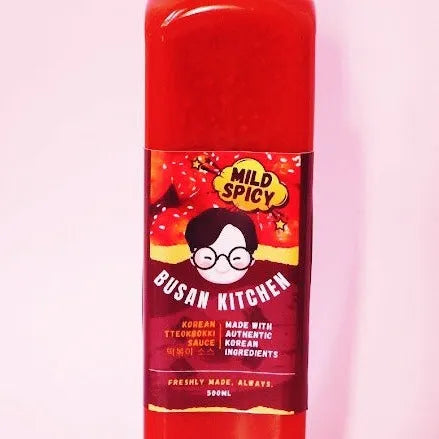 A bottle of Teokbokki Sauce with a label featuring a cartoon character and red berries, indicating the flavor.