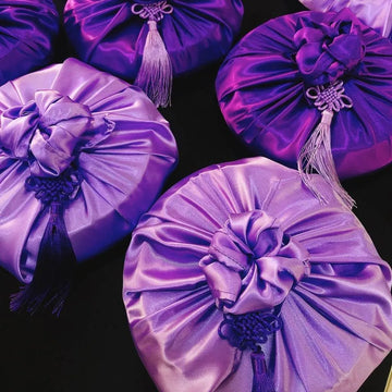 Purple satin bags with tassels on a black background