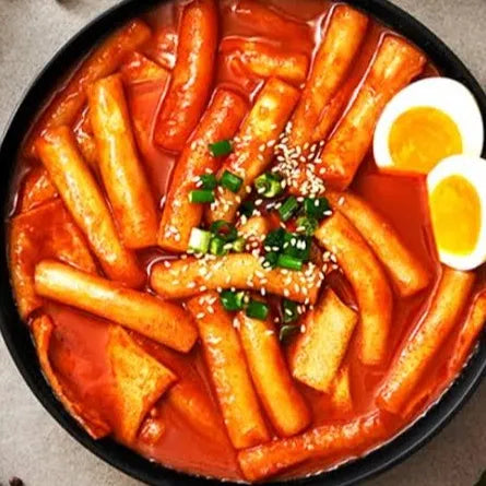 Bowl of spicy Korean Tteokbokki on a gray surface