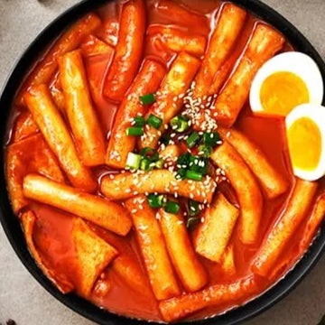 Bowl of spicy Korean Tteokbokki on a gray surface