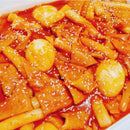 Spicy Korean tteokbokki with tofu on a white plate.