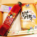 Packaged tteokbokki items including a bottle, noodles, and a package with chopsticks on a white background.