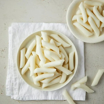 Two bowls of tteokbokki teokk on a light gray surface with a white cloth underneath.