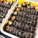Tray of tuna kimbap with colorful fillings in a container.