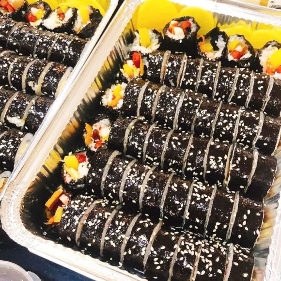 Tray of tuna kimbap with colorful fillings in a container.
